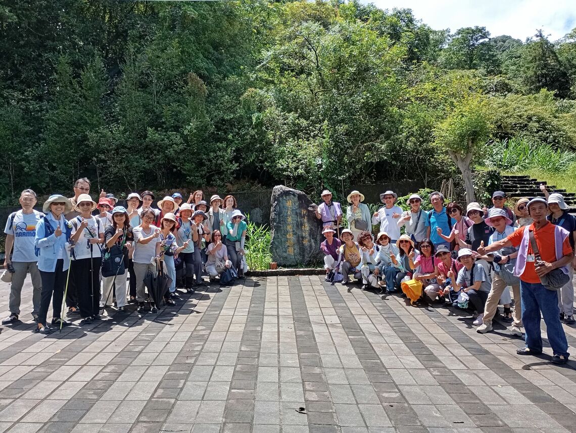 參訪民眾與導覽志工於衛生福利部『國家藥用植物園』石碑前開心合影。圖片