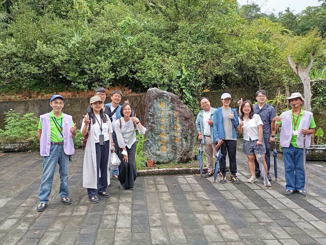 參訪民眾與導覽志工於衛生福利部『國家藥用植物園』石碑前開心合影。圖片